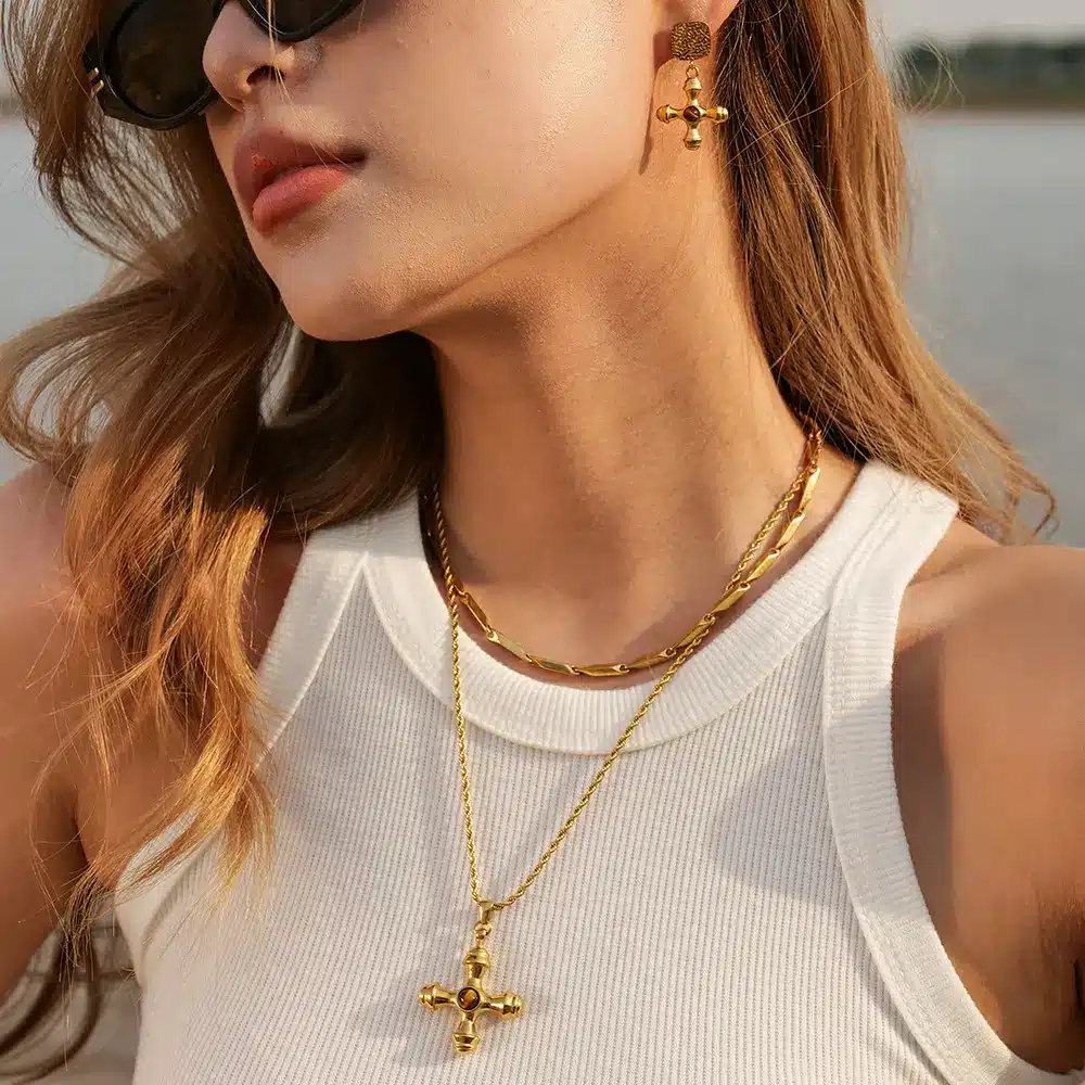 Side profile of model wearing gold plated stainless steel cross necklace