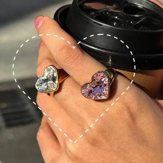 Stainless Steel Jewelry 35 Two gold heart shaped rings on hand holding cup - Waterproof Jewelry