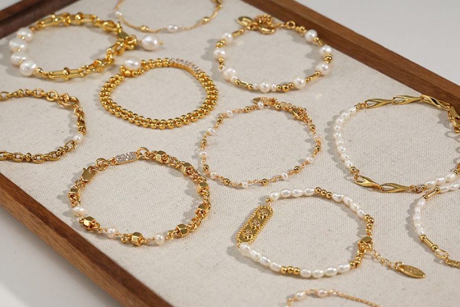 Brass Jewelry 84 Gold-tone chain and bead bracelets with white pearl-style details arranged on a display tray