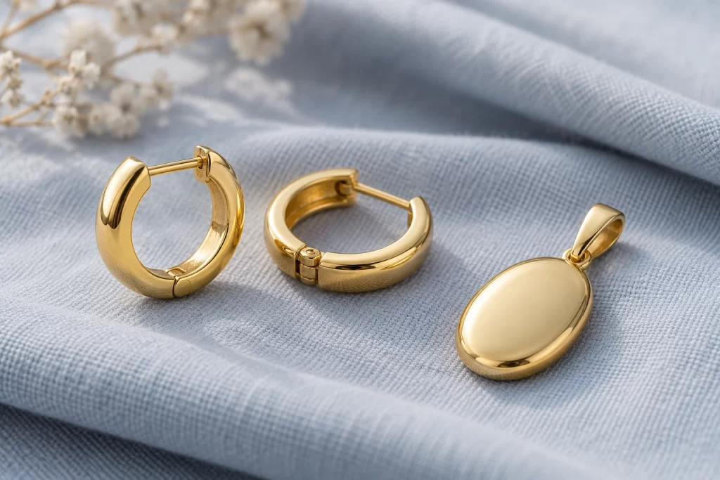 Gold-Plated Jewelry: Layers, Labels and Quality Checks 1 Gold-colored hinged hoops and an oval pendant on pale fabric