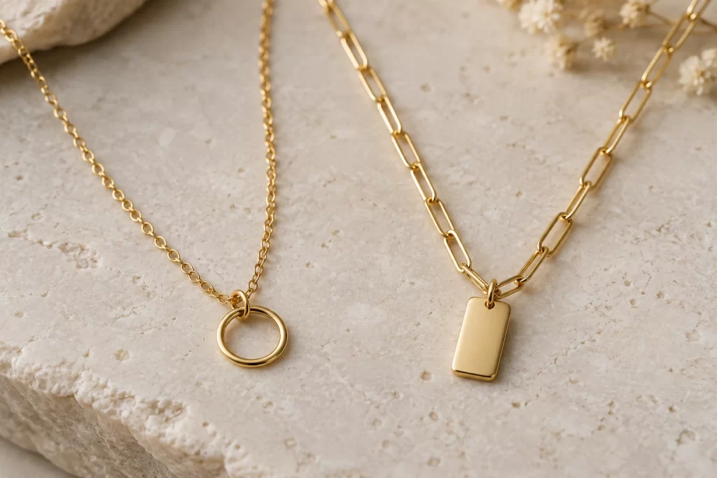 Two gold-colored necklaces with different link and pendant shapes