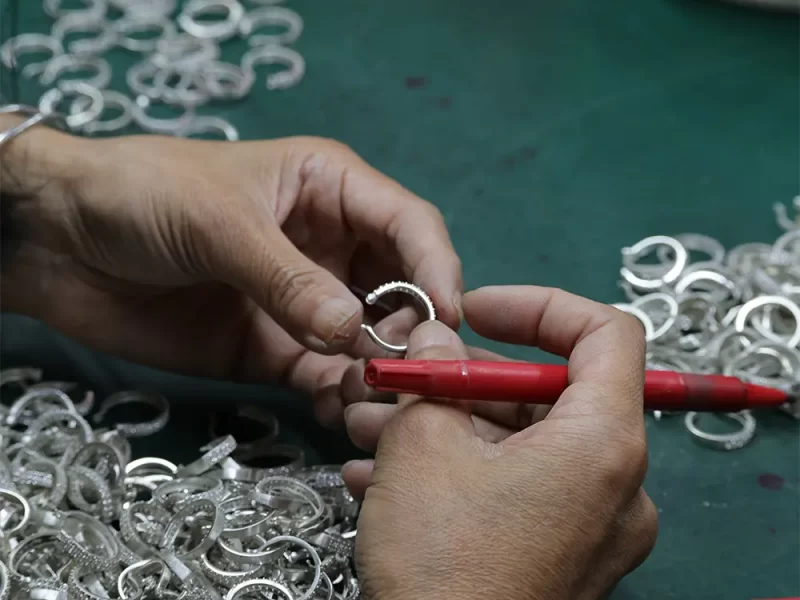 Close-up of hands assembling silver jewelry with precision tools
