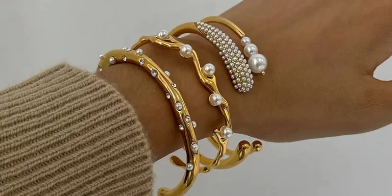 Wholesale Bracelets And Charms Stylish gold-plated copper bracelets stacked on a model's wrist